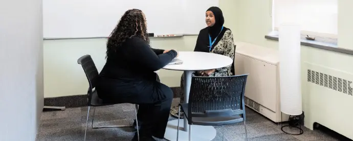 Two people sit around a small round table having a conversation