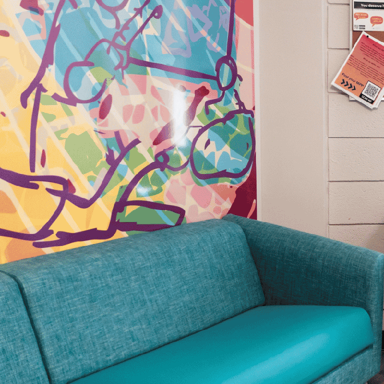 A blue couch in front of a colourful mural